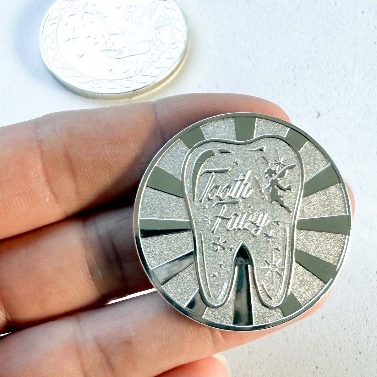 Silver tooth fairy coin held in hand, small magical keepsake for children